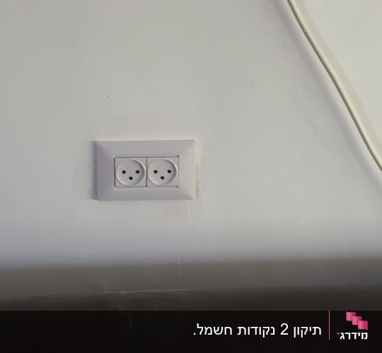 שקע חשמל כפול על קיר לבן עם כבל חשמל